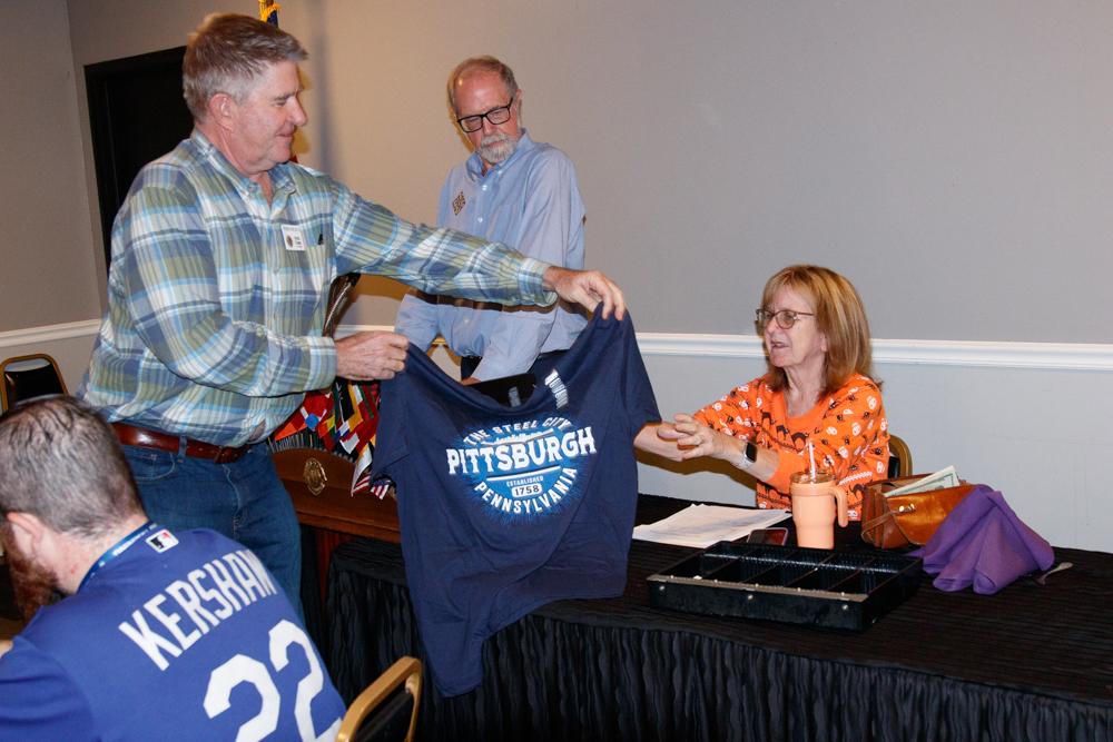 Lion Mark handing the T shirt he auction off to Lion Karen